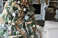 a vintage rustic Christmas tree with lights, beaded garlands, pinecones, burlap ribbons, white ornaments and snowflakes is lovely