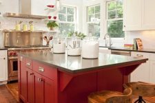 a white kitchen with black stone countertops and a red kitchen island plus vintage pendant lamps is super bold and elegant