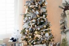an elegant modern Christmas tree with white, silver, black marble and gold ornaments, lights and striped ribbons is very elegant