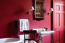 an exquisite red and burgundy bathroom with burgundy walls, a red door, a burgundy bathtub and vintage applainces and furniture