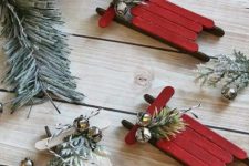 red and white sleigh Christmas ornaments of popsicle sticks with evergreens and bells can bea easily DIYed