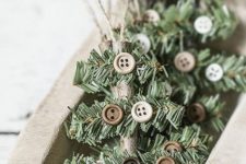 rustic Christmas ornaments made of sticks, evergreens, buttons and twine imitate Christmas trees and look very chic
