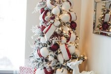 04 a bold Christmas tree with lights, striped ribbons, red and white ornaments, faux fur and pillows under the tree and some toys