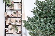 04 a ladder decorated with pinecones, greenery, copper and black ornaments and gifts attached to it is a modern decoration