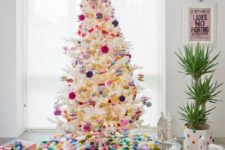 10 a white Christmas tree decorated with bold pompom ornaments and with a colorful pompom tree skirt and a ball on top