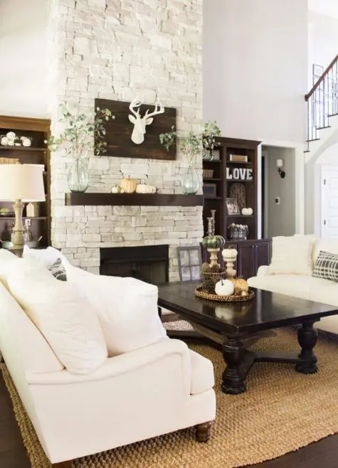 a stylish farmhouse space with a whitewashed stone fireplace, a dark stained mantel and some furniture and white sofas