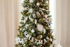 11 a very glam and chic Christmas tree with lights, letter banners, white and silver ornaments, a white bow and cotton under the tree