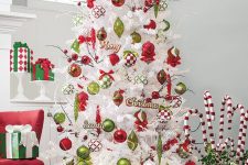 13 a whimsical white Christmas tree decorated with green and red ornaments of various looks and a red Santa hat on top