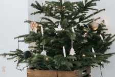 19 a Nordic Christmas tree with lights, porcelain and wooden ornaments and with old crates cover the tree base