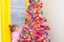 21 a pink Christmas tree decorated with colorful chains and with a red tire as a cover for the base of the tree