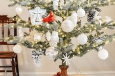 25 a vintage rustic Christmas tree with white and plaid ornaments and pinecones placed into a vintage wooden candleholder is a cool idea