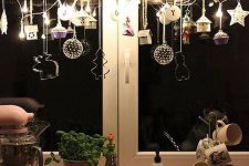 25 window Christmas decor of a branch with clay ornaments, cookie cutters, lights and mini houses and acupcakes is chic
