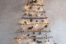 34 a wall-mounted stick Christmas tree with lights, silver and white ornaments is a lovely natural idea for winter holidays