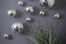 38 silver Christmas ornaments of various sizes attached to the wall bring a festive feel to the space but ina very modern way