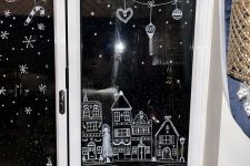 Christmas window decor done with paint, with houses, snow and snowflakes and some ornaments