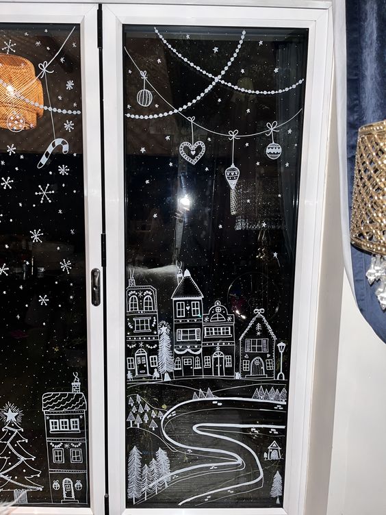 Christmas window decor done with paint, with houses, snow and snowflakes and some ornaments