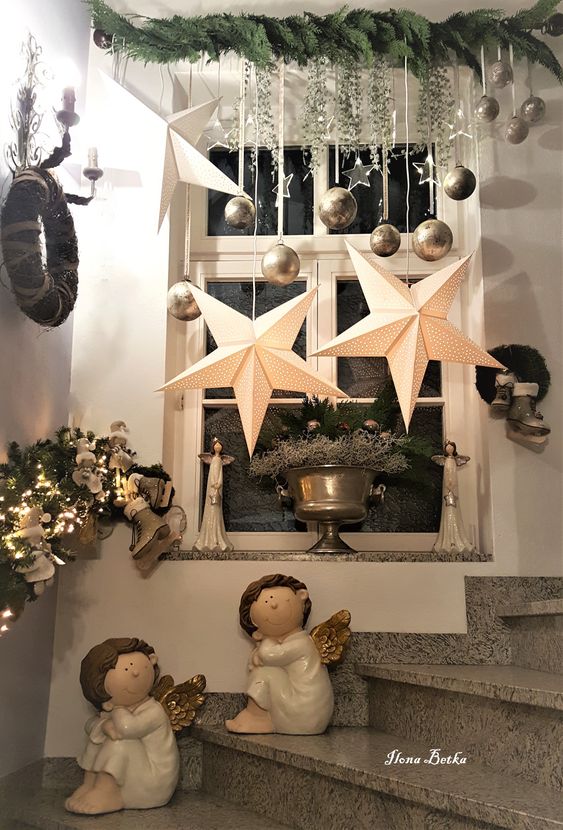 Christmas window decor with silver ornaments, clear stars, greenery and large star lamps is super catchy