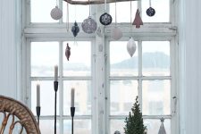 Scandinavian window decor with a branch and ornaments hanging on it is a cool and easy decor idea for the space