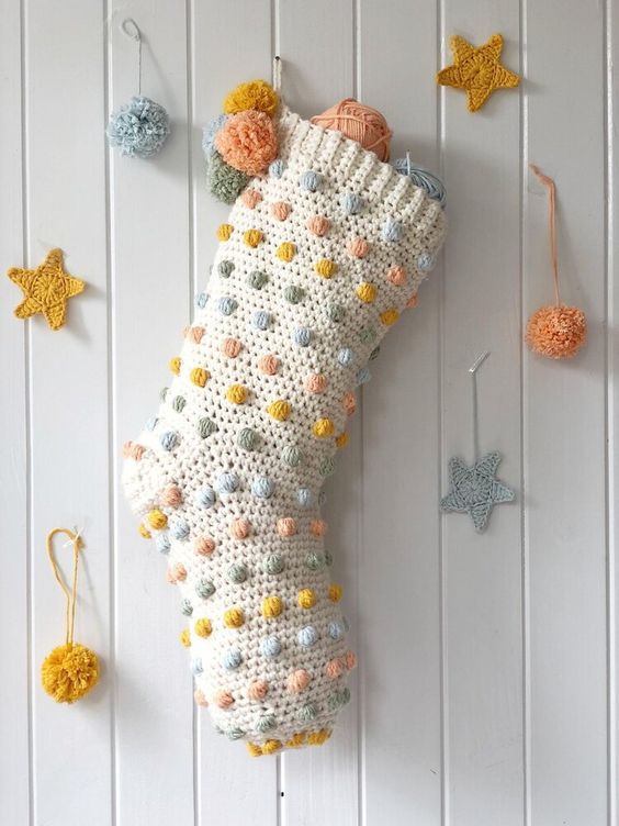 a Christmas stocking dotted wiht pastel pompoms is a cool decor idea for the holidays