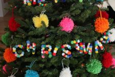 a Christmas tree with coloful pompom ornaments and colorful pompom letters is a lovely idea for the holidays