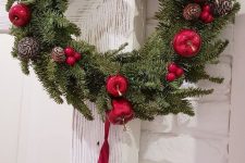 a beautiful Christmas wreath of fir, red berrries, apples, pinecones and silver bells hanging on red ribbons is lovely
