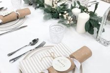 a beautiful neutral Christmas tablescape with a white tablecloth and napkins, white porcelain, an evergreen runner and white berries