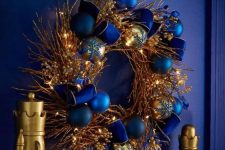 a bold Christmas wreath with gilded branches and twigs, lights and navy and blue ornaments is a bold statement