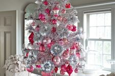 a bold vintage silver Christmas tree with pink and red ornaments and deer figurines under the tree is a catchy idea