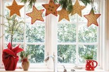 a branch with fir twigs and hanging bright stars is a cozy idea with a strong rustic feel, it will be great not only for kitchens