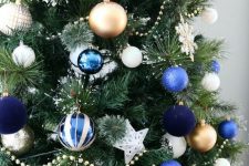 a bright Christmas tree with white, gold, blue and navu ornaments and white snowflakes is amazing and bold