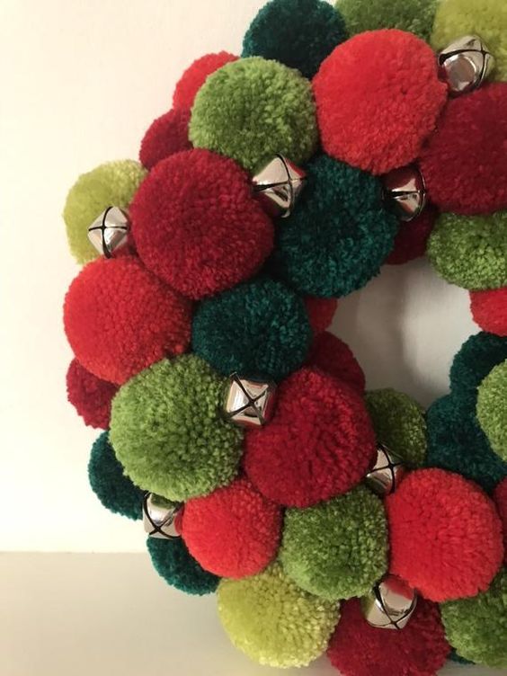 a bright red and green pompom Christmas wreath with little bells is a bold holiday decoration you can make yourself