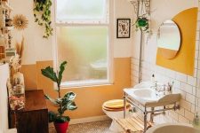 a cheerful bathroom with white subway tiles and printed ones, an oval tub, a cabinet, a free-standing sink, some plants and decor