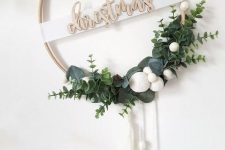 a chic Nordic Christmas wreath with wooden letters, greenery, snowballs and tassels is perfect to decorate your home