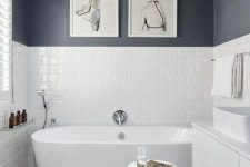 a chic black and white bathroom with a mosaic floor, black and white walls, a tub and a white vanity