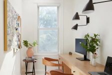 a chic modern home office with a double desk, leather chairs, a memo board, black sconces and a table with a plant