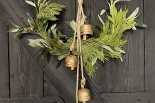 a chic vintage Christmas wreath with greenery, foliage, berries and vintage bells on rope is a very cool decoration