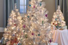 a cluster or silver Christmas trees decorated with colorful ornaments and lights, with stacks of gift boxes for refined holiday decor