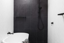 a contrasting bathroom with herringbone and large scale tiles, an oval tub, a black stool and black fixtures