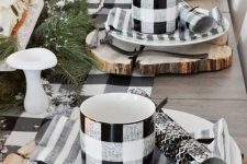 a cozy and simple buffalo check Christmas tablescape with wood slice placemats, striped napkins, buffalo check mugs and a table runner, evergreens and mushrooms
