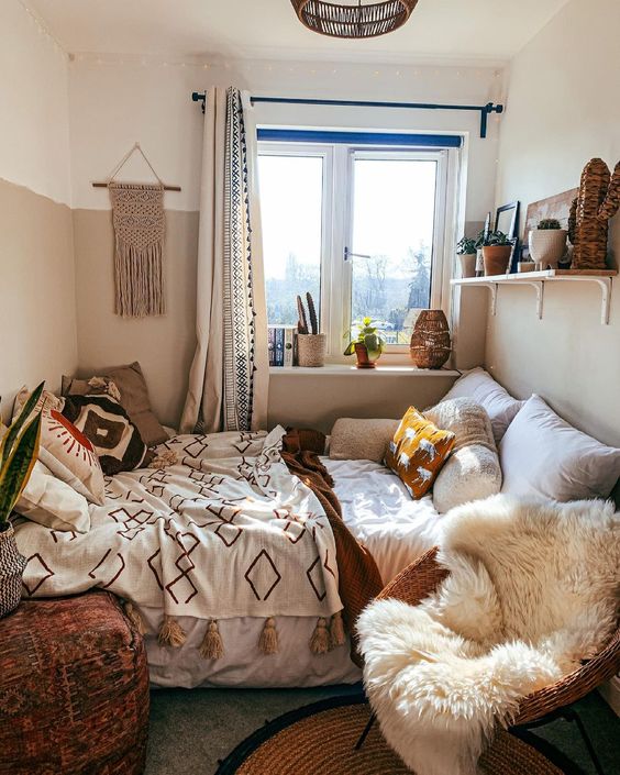 a cozy boho bedroom wiht a bed, a shelf with decor, a chair with faux fur and a pouf plus a lot of boho decor