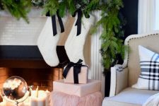 a fir garland, mini houses, silver decorative trees, white stockings with black bows and pink gift boxes for a preppy lam look