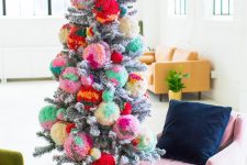 a flocked Christmas tree decorated with colorful oversized ombre pompoms insteaf of usual ornaments is a fun idea