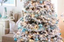 a flocked Christmas tree with lights, silver and tiffany blue ornaments, snowy pinecones and starfish is a fresh idea for a beach Christmas space