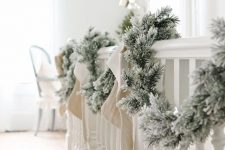 a flocked fir garland with neutral stockings is a pretty and easy vintage rustic staircase decor idea for Christmas