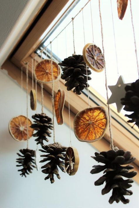 a garland of pinecones and citrus slices is a beautiful and cool idea for decorating your window in natural style