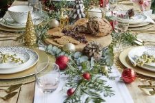 a glam Christmas table with gold placemats and chargers, mini Christmas trees and ornaments, greenery, red ornaments and a gorgeous Christmas cake