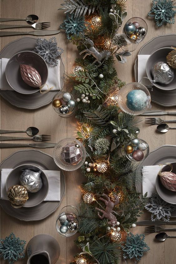 a glam Christmas tablescape with a lush greenery runner, vintage lights, metallic ornaments, grey porcelain and berries is wow