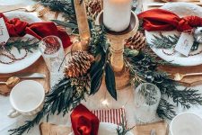 a lovely rustic Christmas table with wooden chargers, snowflake plates, wooden candleholders, greenery, pinecones and gold cutlery