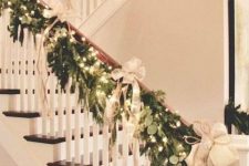 a lush greenery and fir garland with lights, neutral bows and ribbons for elegant and chic Christmas railing decor