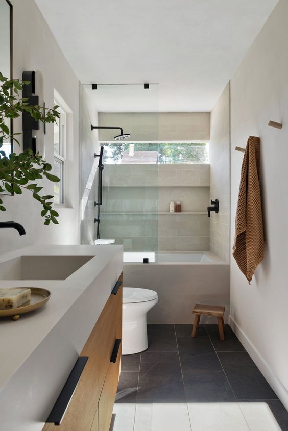 a minimalist bathroom with a window, a bathtub with a shower, a floating vanity and a stone countertop and a stool